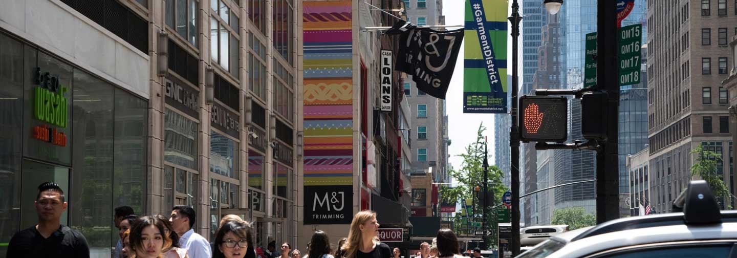 A glance down a buys street in New York City featuring a banner from the Garment District